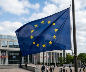 Na obrazie widać wielką flagę Unii Europejskiej, dumnie łopoczącą na wietrze